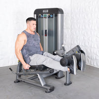 Thumbnail for Man using a gray leg extension curl combo machine in a gym.