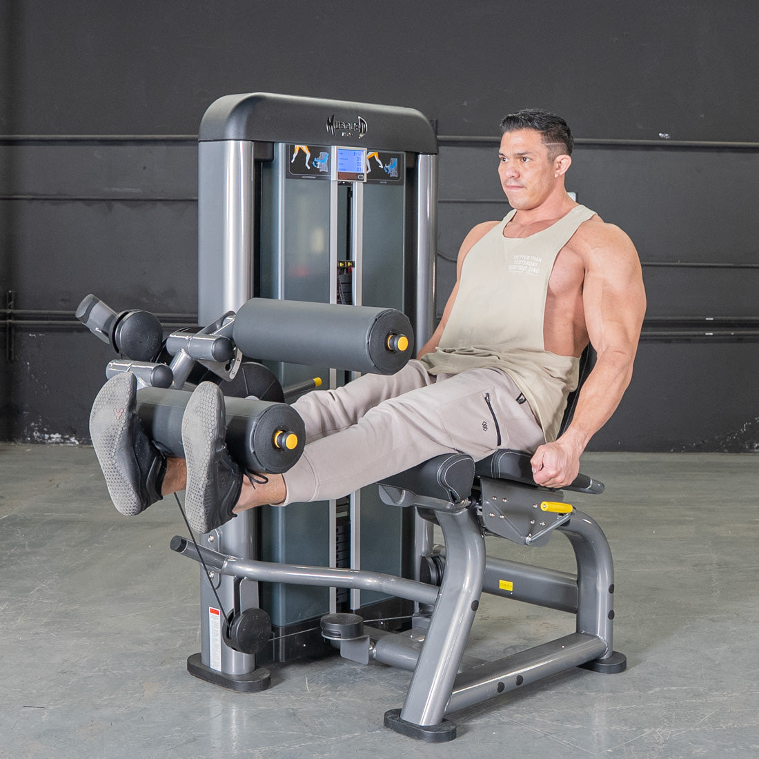 Man using a grey leg extension curl combo machine in a gym.