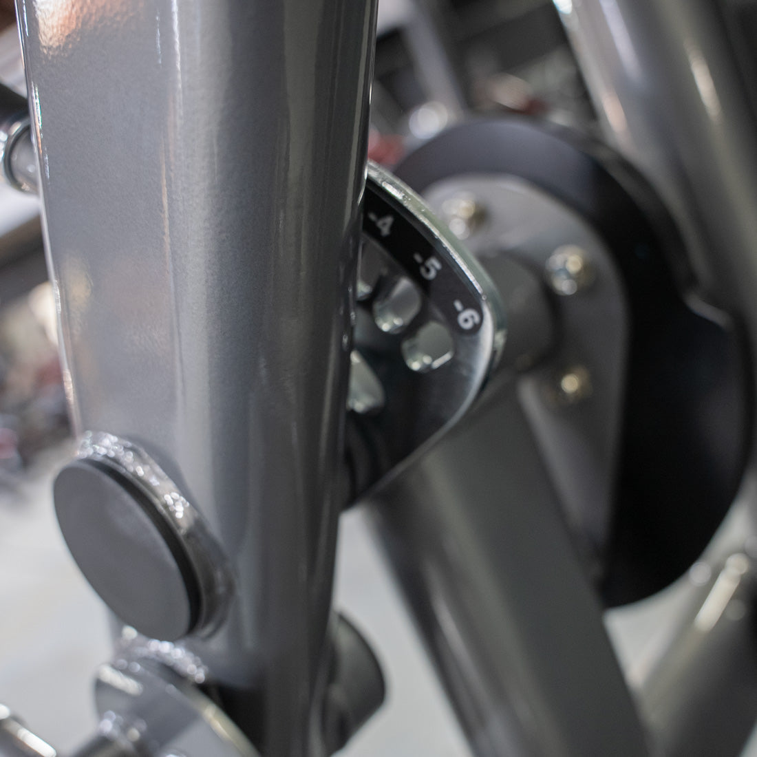 Close-up of a leg extension machine showing the gray frame and a numbered adjustment dial.