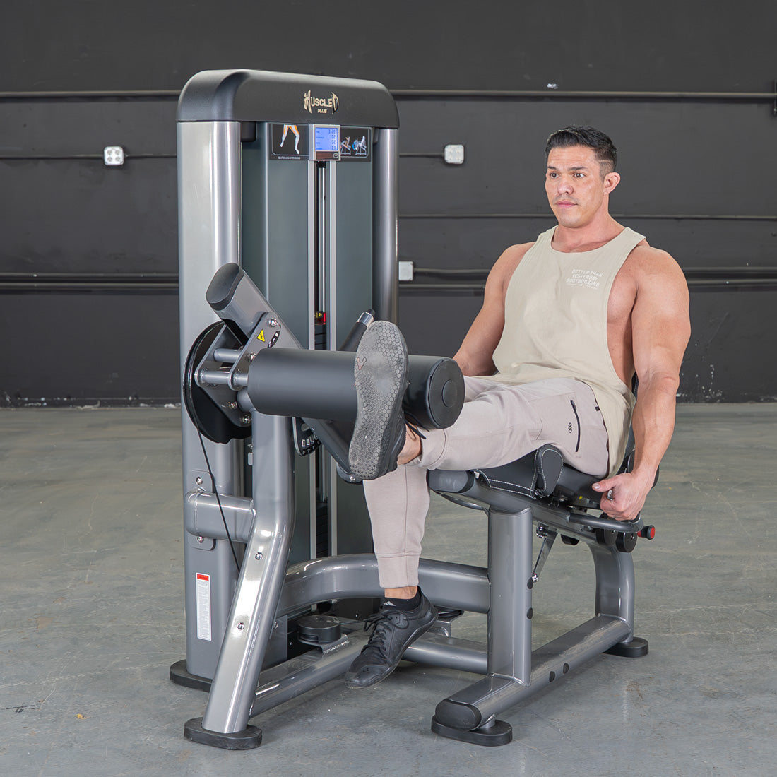 Man using a grey and black leg extension machine in a gym.