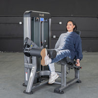 Thumbnail for Woman using a gray leg extension machine in a gym.