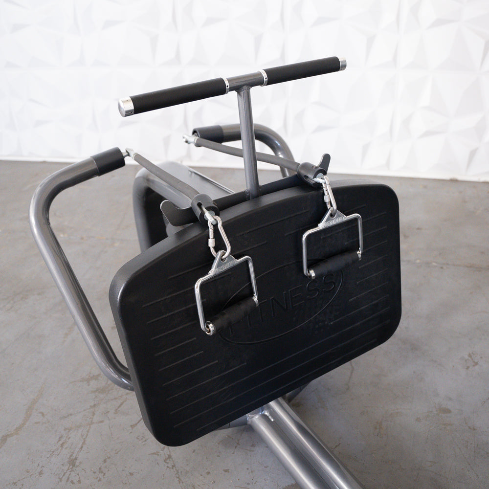 Close-up of a long pull row machine with a black footplate and two handles attached by carabiners.