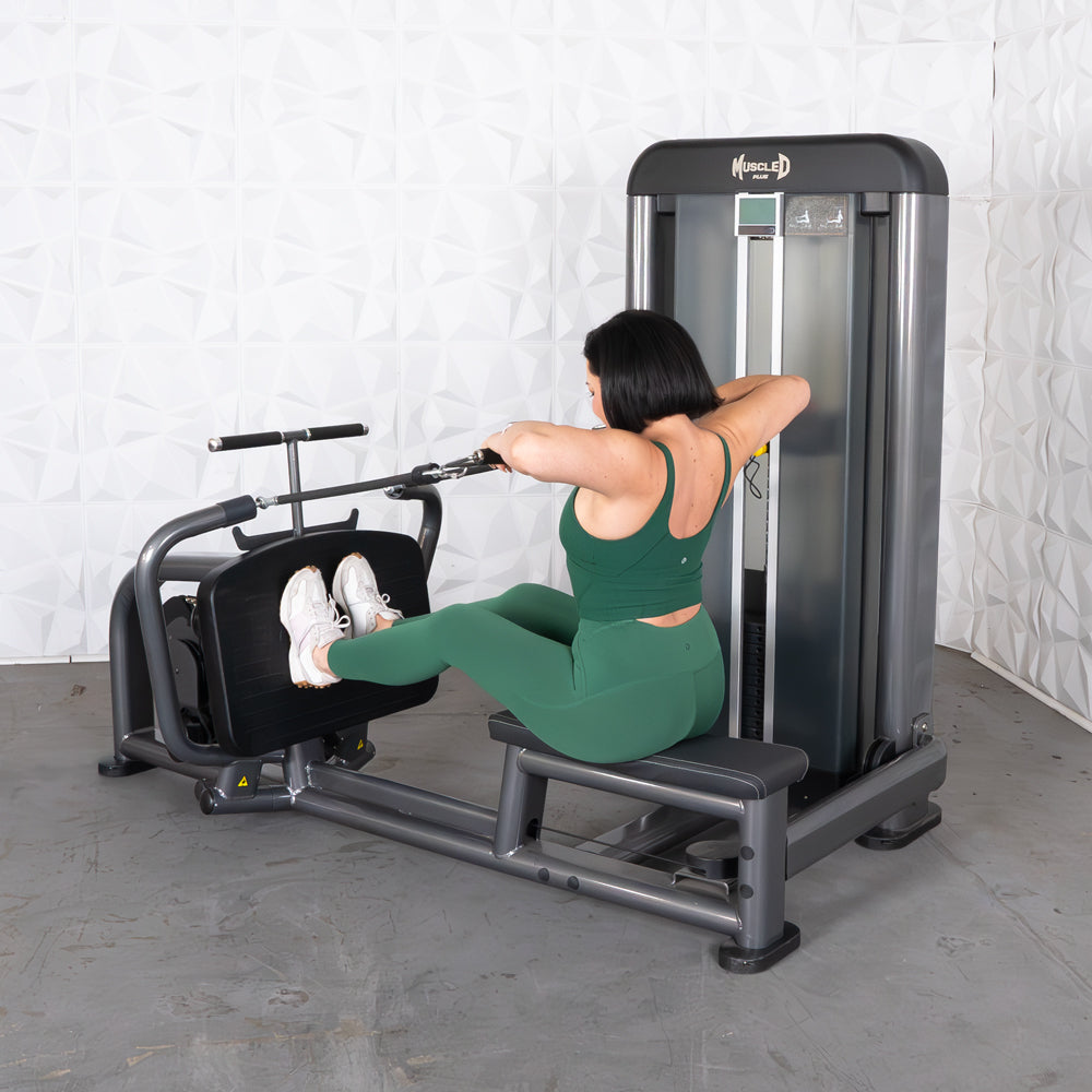 Woman in green activewear using a long pull row machine with her feet on the footplate.