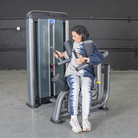 Thumbnail for Woman using a gray and black rotary torso machine in a gym.