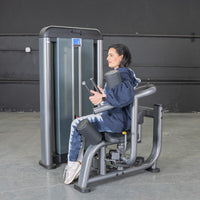 Thumbnail for Woman in blue hoodie and tie-dye pants using a gray rotary torso machine.