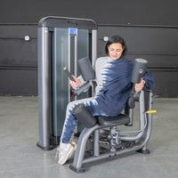 Thumbnail for Woman using a gray rotary torso machine with black pads and a weight stack.