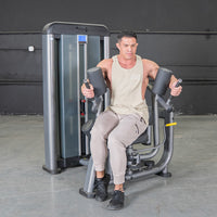 Thumbnail for Man using a gray rotary torso machine with black padded armrests and an adjustable seat.