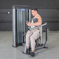 Thumbnail for Man using a gray rotary torso machine with an adjustable seat and pin selectorized weights.