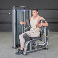 Thumbnail for Man using a gray rotary torso machine with black padding in a gym.