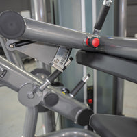 Thumbnail for Close-up of a leg curl machine's gray frame, black padding, and red adjustment knob.