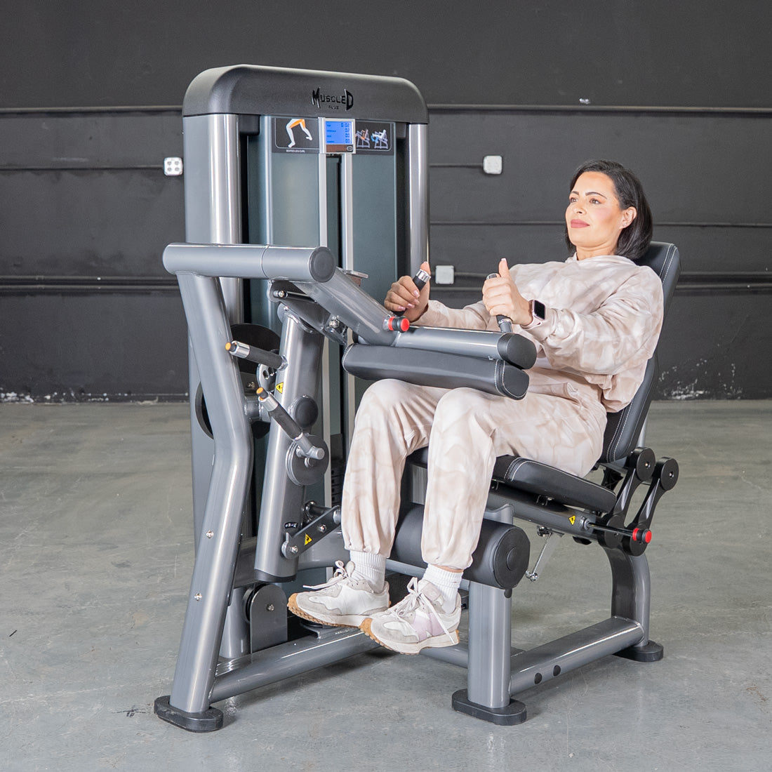 Woman using a seated leg curl machine in a gym.