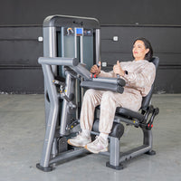 Thumbnail for Woman using a seated leg curl machine in a gym.