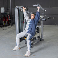 Thumbnail for Woman in tie-dye sweats using a shoulder press machine in a gym.