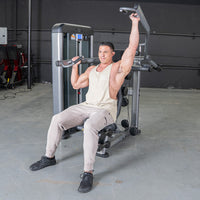 Thumbnail for Man in a gym using a shoulder press machine, one arm extended upwards.