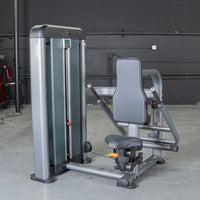 Thumbnail for Gray triceps press machine with black padded seat and backrest, weight stack on left, in a gym setting.