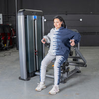Thumbnail for Woman in tie-dye hoodie using a triceps press machine in a gym.