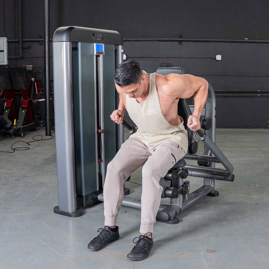 Man using a gray triceps press machine in a gym.