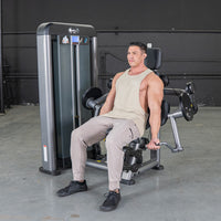 Thumbnail for Man in a tank top and sweatpants using a gray biceps curl machine in a gym.
