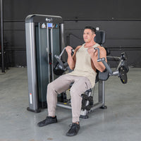 Thumbnail for Man in a tank top and sweatpants performing bicep curls on a gray weight machine in a gym.