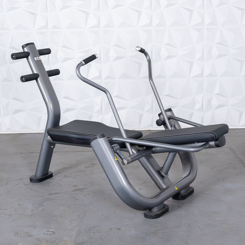 Gray and black ab roller machine with padded seats and handles on a concrete floor.