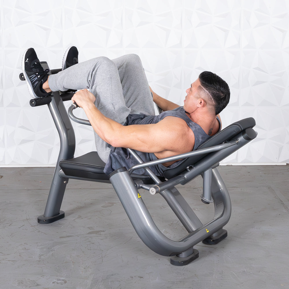 Man in grey tank top and sweatpants using a grey leg raise machine.