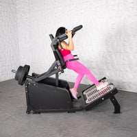 Thumbnail for Woman in pink leggings using a black plate-loaded hack squat machine with weights.