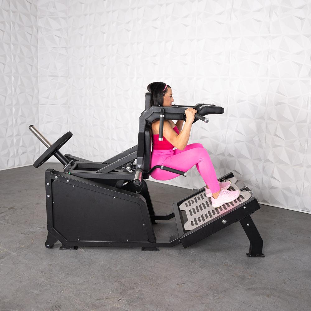 Woman in pink using a black plate-loaded hack squat machine.