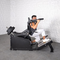 Thumbnail for Man performing a squat on a black plate-loaded hack squat machine with weights.