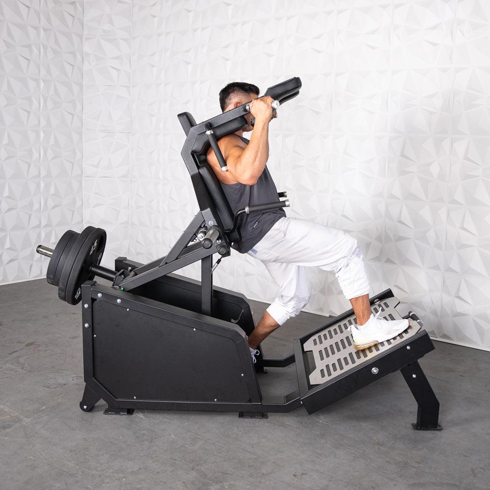 Man performing a squat on a black plate-loaded hack squat machine with weights.