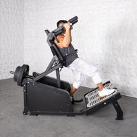 Thumbnail for Man using a black plate-loaded squat machine with weights, performing a front squat.