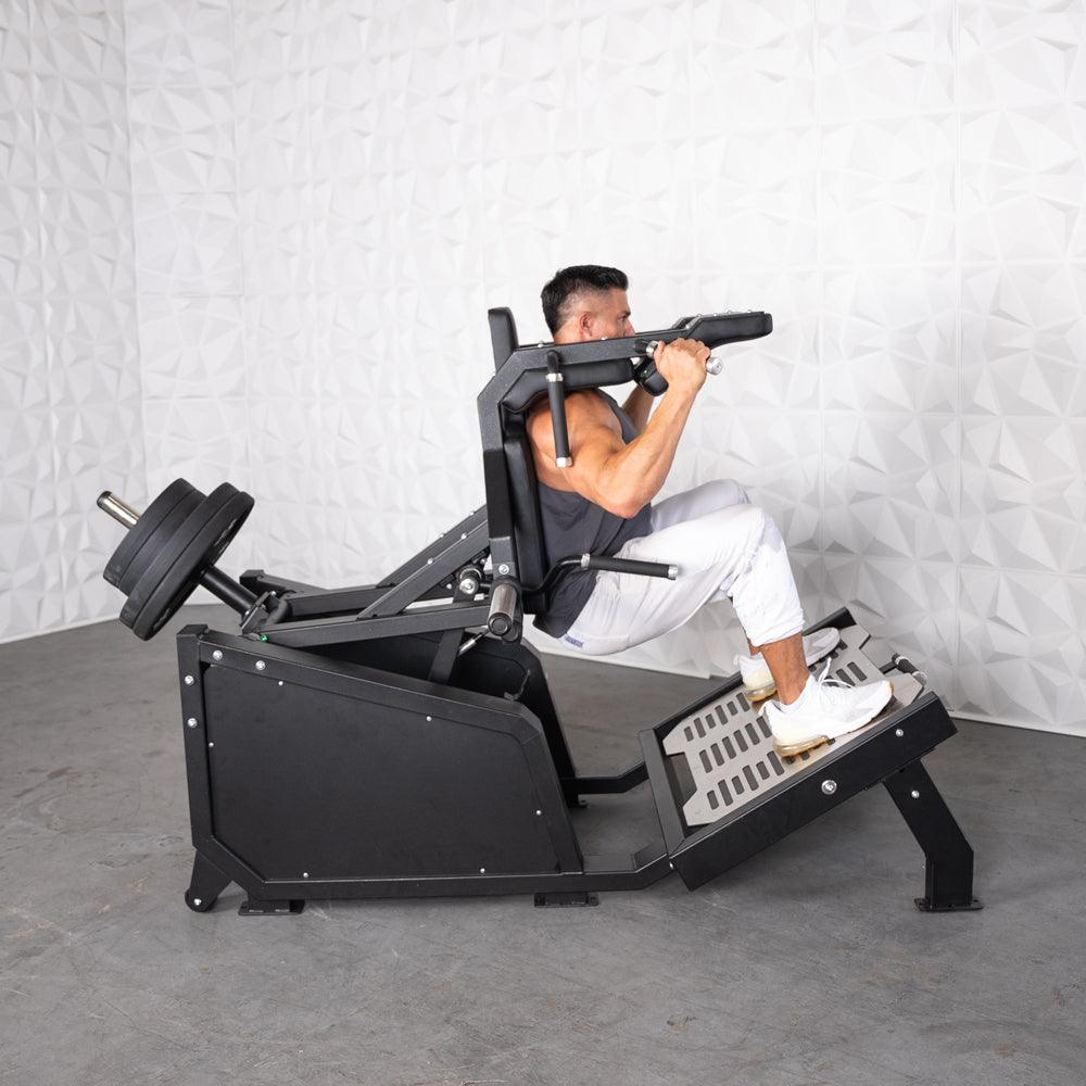 Man performing a squat on a black plate-loaded squat machine with weights.