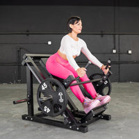 Thumbnail for Woman in pink leggings using a black linear bearing row machine with weight plates.