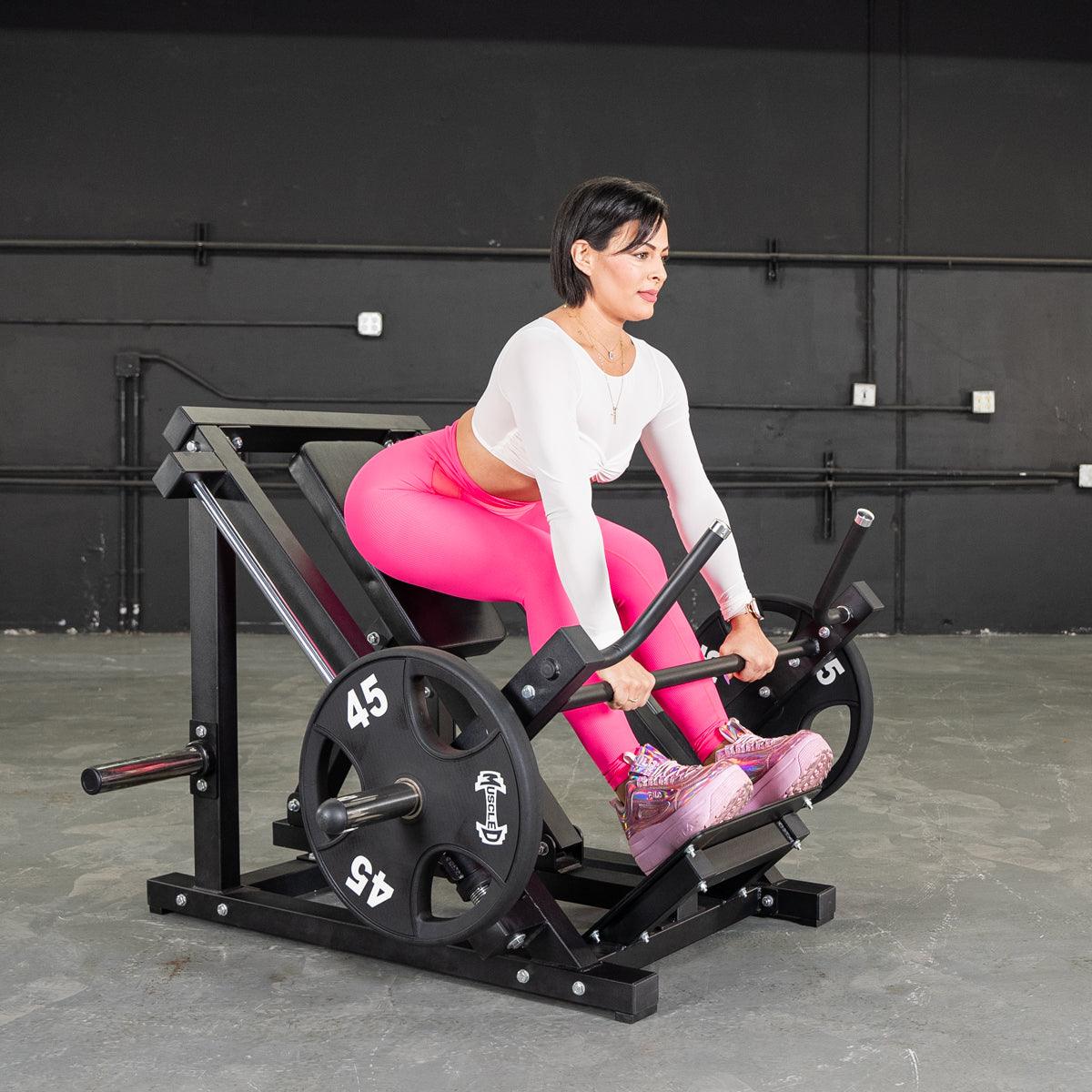 Woman in pink leggings using a black linear bearing row machine with 45lb weight plates.