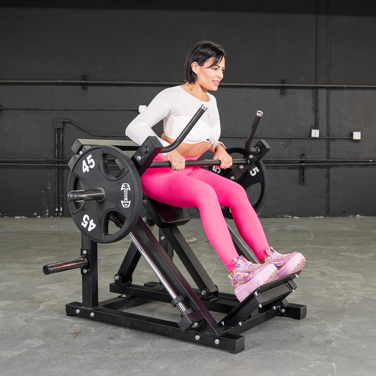 Woman in pink leggings using a black linear bearing row machine with 45lb plates.