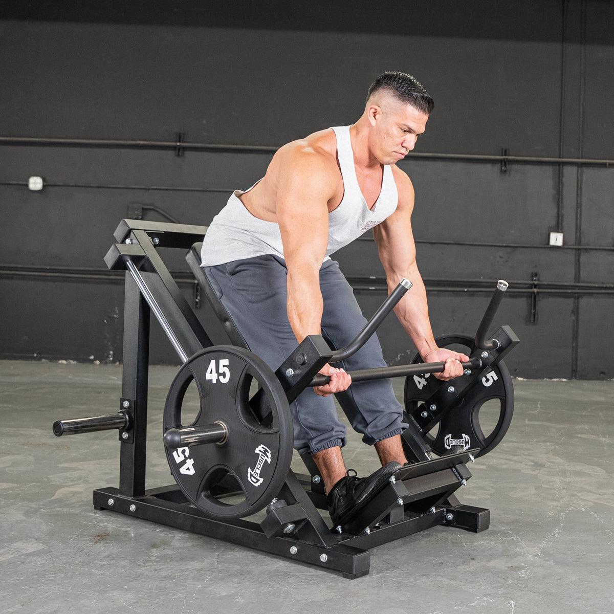 Man using a black linear bearing row machine with 45lb weight plates in a gym.