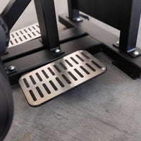 Thumbnail for Close-up of the textured, anti-slip footplate and black frame of the Excel Standing Hip Thrust machine.