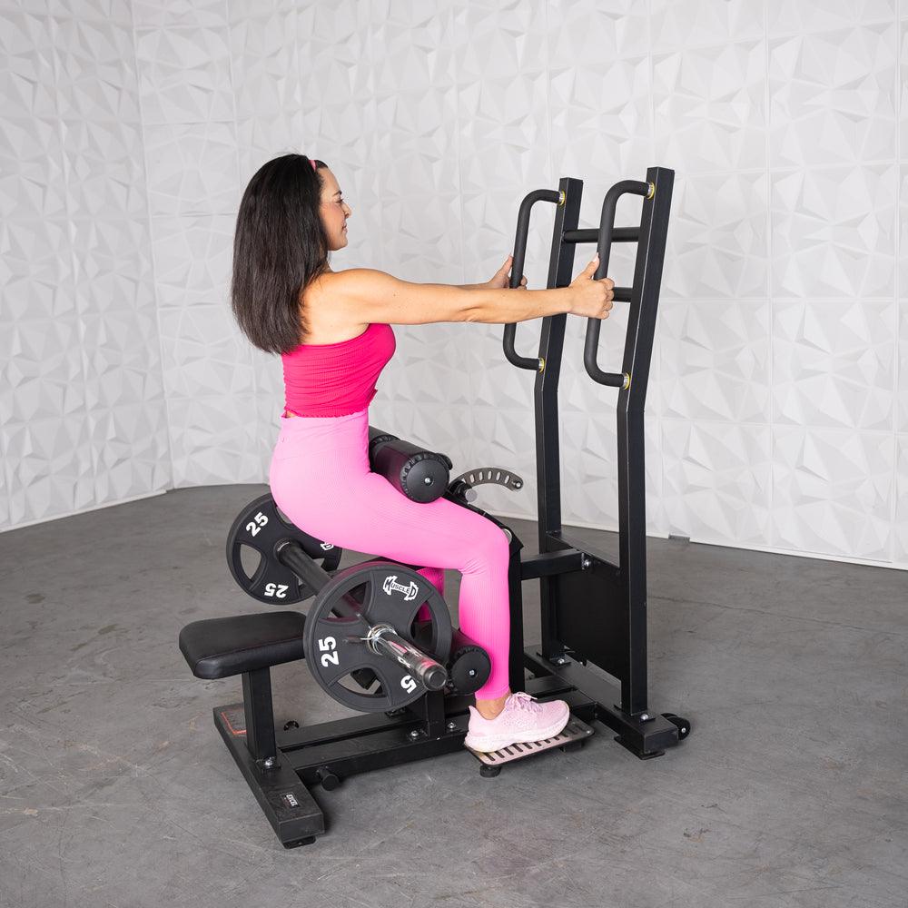 Woman in pink using a black plate-loaded hip thrust machine with 25lb weights.