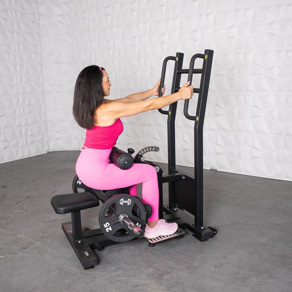 Woman in pink using a black plate-loaded standing hip thrust machine.