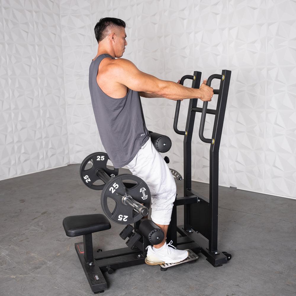Man in gray tank top using a black standing hip thrust machine with 25lb plates.