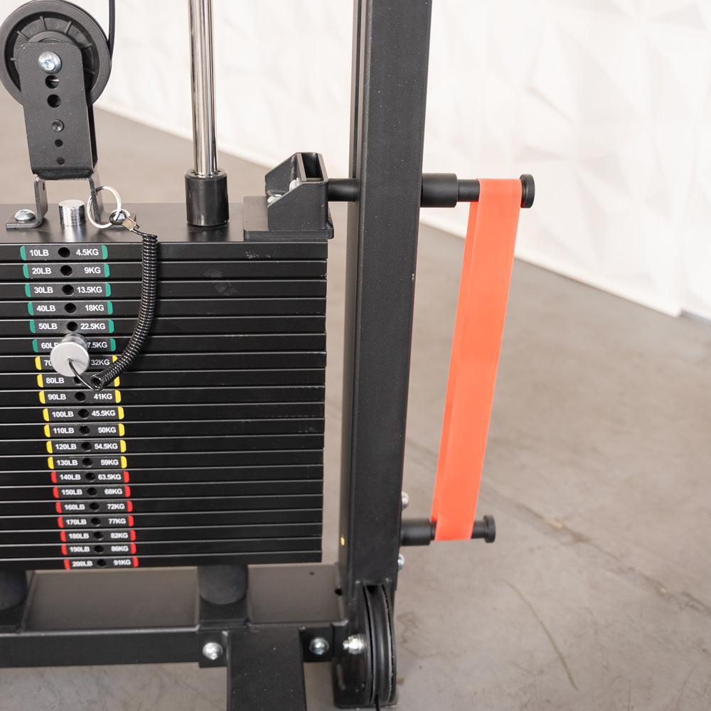 Close-up of a selectorized weight stack with a weight pin and an orange resistance band attached to the frame.