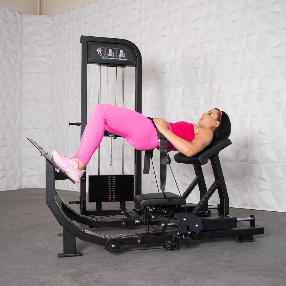 Woman in pink performing hip thrusts on a black selectorized glute drive machine.