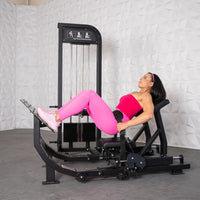 Thumbnail for Woman in pink workout gear using a black selectorized hip thrust glute machine.