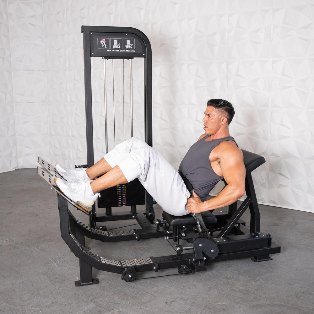 Man using a black selectorized hip thrust glute machine with white background.
