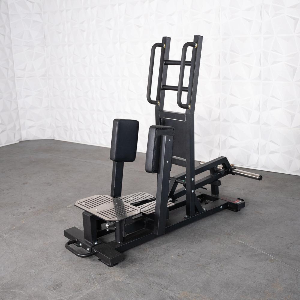 Black standing hip abductor machine with padded supports, footplates, and a plate load bar.