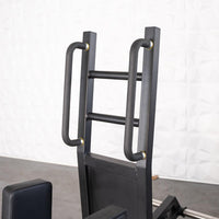 Thumbnail for Close-up of the black metal frame and padded handles of the standing hip abductor machine.