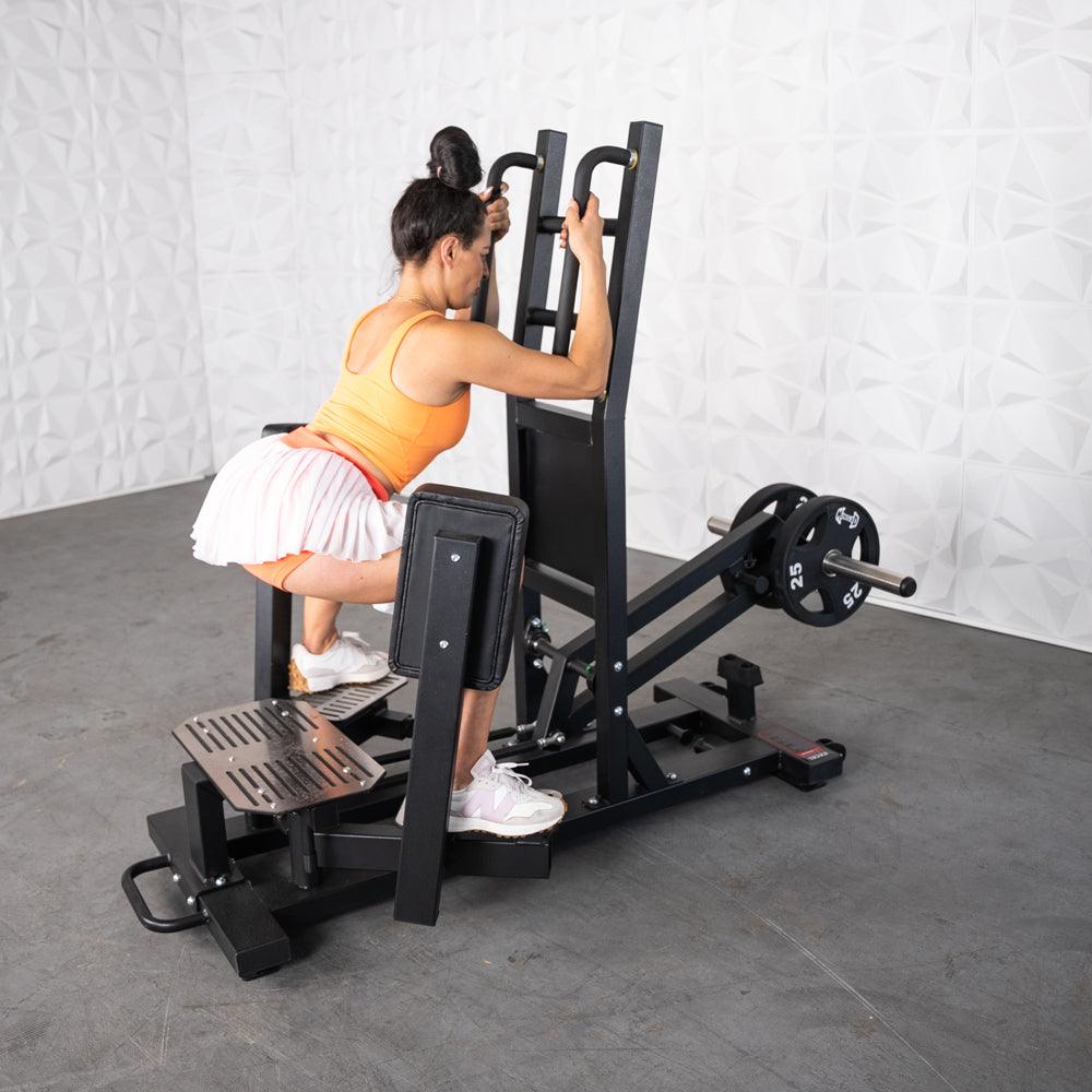 Woman using a black plate-loaded standing hip abductor machine with 25lb weights.