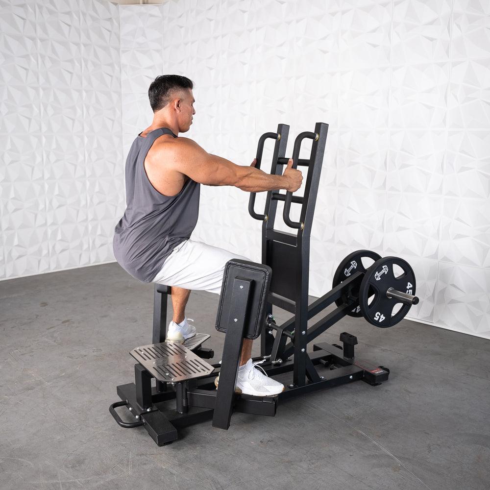 Man using a black standing hip abductor machine with plate weights in a gym.