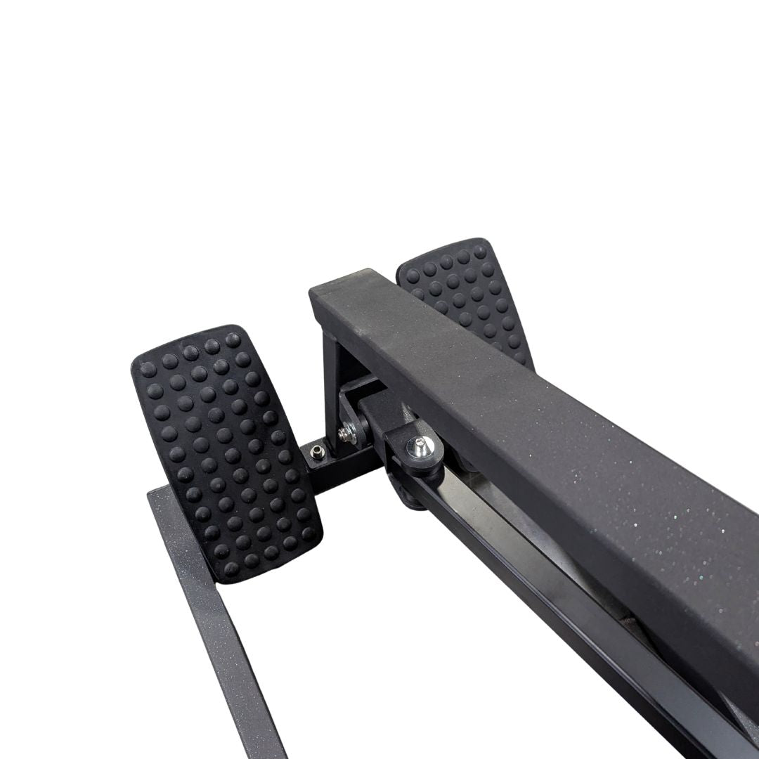 Close-up of the textured footrests and frame of a black T-bar row machine.