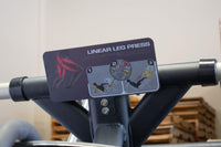 Thumbnail for Instructional placard for a linear leg press machine, showing muscle groups and exercise steps.