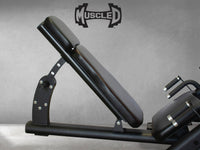 Thumbnail for Black leg press machine with an adjustable back pad and handles, against a gray wall.